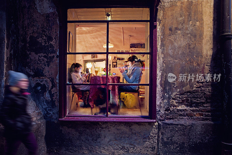 Girlfriends are sitting and texting in a cafe